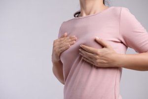Женщина сжимает больную грудь Женщина мнет больную грудь